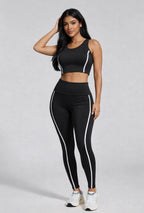 Woman wearing a black athletic outfit with white accents on a gray background
