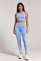 Woman wearing a light blue athletic outfit with white stripes on a plain background