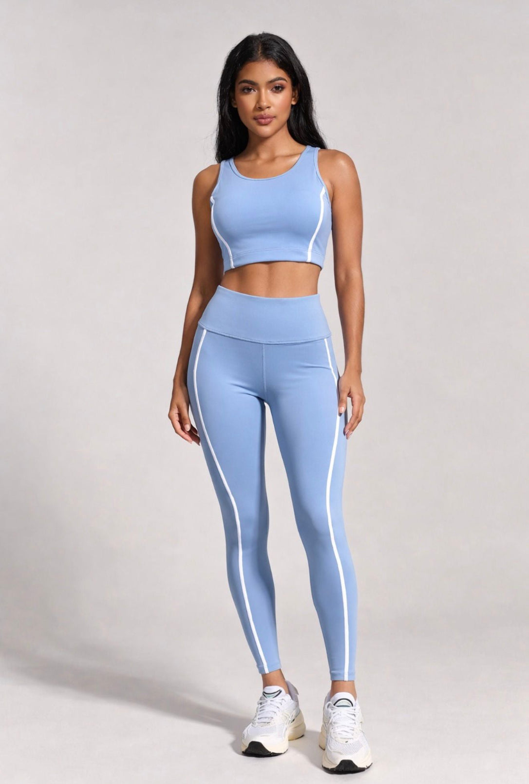 Woman wearing a light blue athletic outfit with white stripes on a plain background