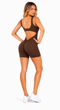 Woman wearing a brown cut-out sports outfit on a white background